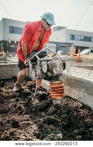 Industrial Portrait Of Worker Using Vibratory Tamper Soil Compactor