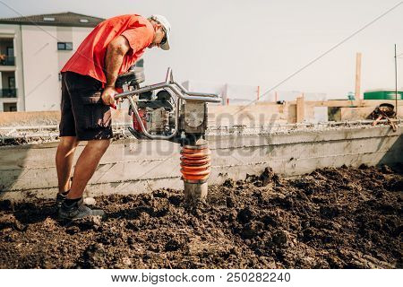 Professional Worker, Industry Details. Worker Using Vibratory Compactor At House Foundation