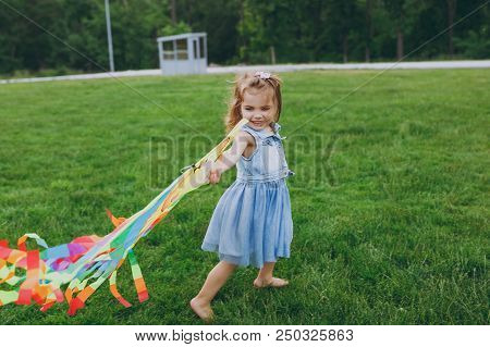 Smiling Little Cute Child Baby Girl In Denim Dress Walking, Play With Colorful Kite And Have Fun In 
