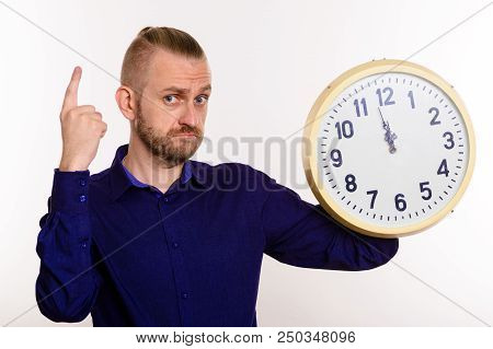 A Stylish Man Holds A Large Wall Clock And Points His Finger Up On White Background