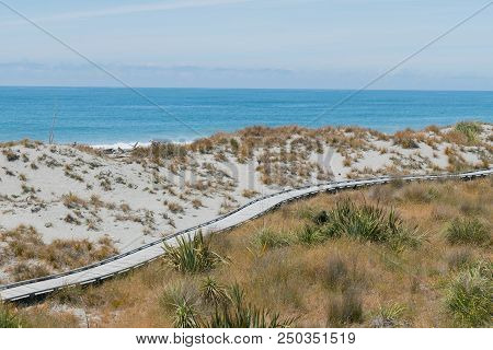 Sand Beack With Wooden Walking Path Over Ocean Skyline Background