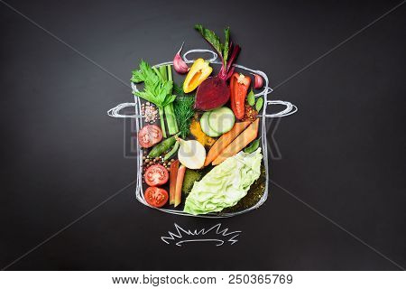 Food Ingredients For Blending Creamy Soup On Painted Stewpan Over Black Chalkboard. Top View With Co