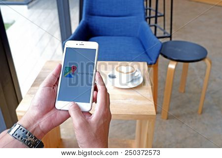 A Man Sit In Cafe Holding Mobile With Google Maps Screen