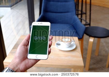 A Man Sit In Cafe Holding Mobile With Grab Screen