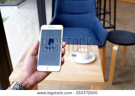A Man Sit In Cafe Holding Mobile With Paypal Screen