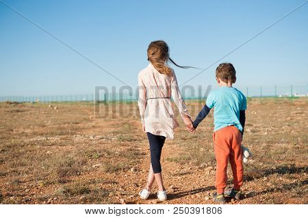 Small Brother And Sister Refugees Holding Hands Standing Among Desert On State Border