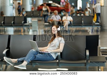 Young Calm Traveler Tourist Woman With Headphones Listening Music Working On Laptop, Wait In Lobby H