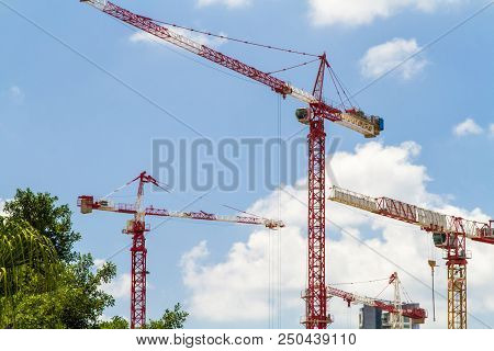 Construction Cranes, Tower Cranes Against The Blue Sky With Clouds