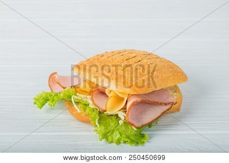 Pressed And Toasted Double Panini With Ham And Cheese Served On Sandwich Paper On A Wooden Table