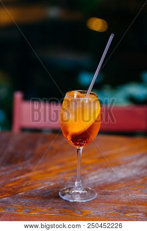 Vertical Shot Of Fresh Sweet Aperol Spiritz Cocktail With Slice Of Orange, On Wooden Table In Cafe. 