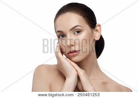 Beatiful Model Posing With Naked Shoulders Looking At Camera With Big Blue Eyes. Touching Face Tende