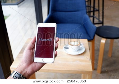 A Man Sit In Cafe Holding Mobile With Pinterest Screen