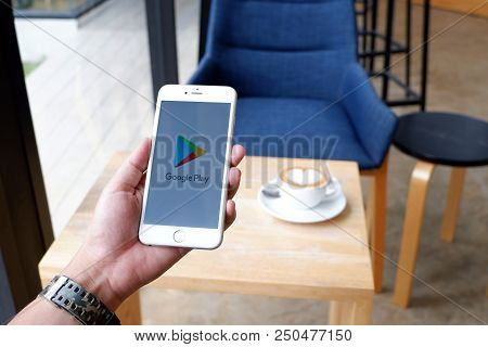 A Man Sit In Cafe Holding Mobile With Google Play Screen