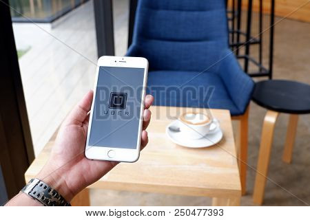 A Man Sit In Cafe Holding Mobile With Uber Screen