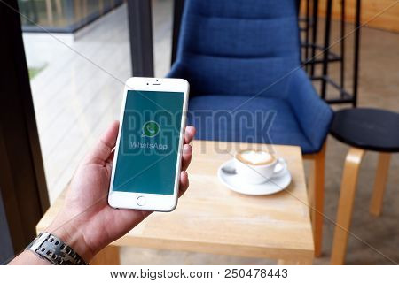A Man Sit In Cafe Holding Mobile With Whatapp Screen