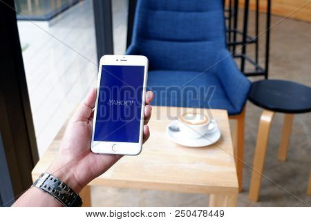 A Man Sit In Cafe Holding Mobile With Yahoo Screen