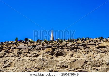 Broken Glass On Top Of Stone Wall As Anti Climb Measure With Church Steeple Against Clear Blue Sky