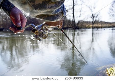 A Fisherman Catches A Fish. Spinning Reel Closeup. Shallow Depth Of Field On The Spinning Reel.