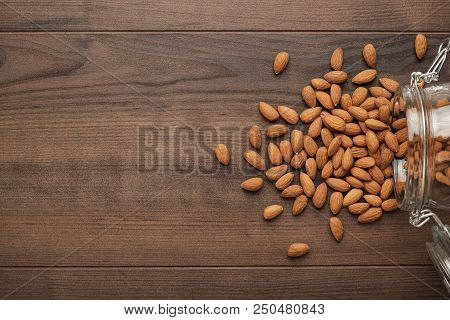 Overturned Jar Of Almonds. Glass Can Full Of Almonds. Almonds Background. Many Almonds On The Table