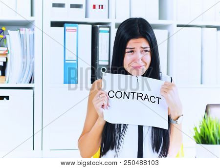 Young Unhappy Female Office Worker Ripping Contract At The Desk.