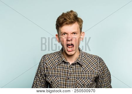 Emotional Breakdown. Angry Enraged Infuriated Crazy Man Screaming. Portrait Of A Young Guy On Light 