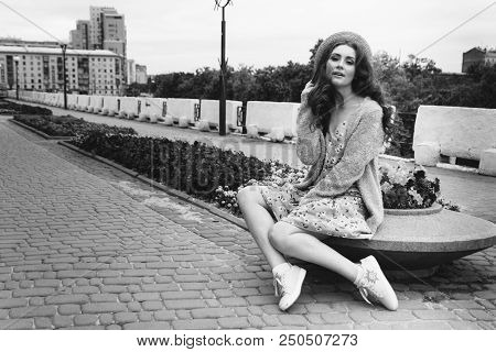 A Beautiful Girl In A Hat, Keeps The Hair From The Wind. Sits On Scraps. Walk Around The City. Portr