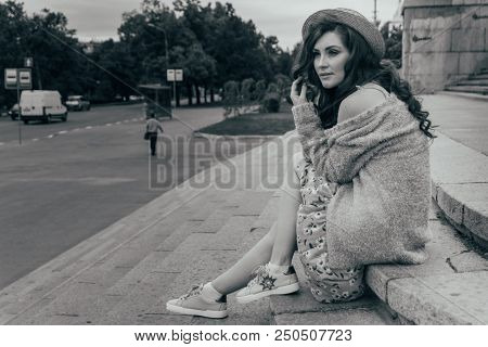 A Beautiful Girl In A Hat, Keeps The Hair From The Wind. Sits On Scraps. Walk Around The City. Portr