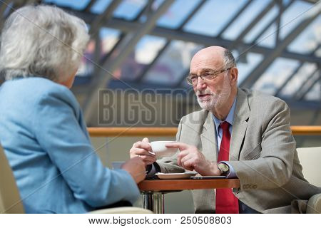 Senior People Talking In Cafe Drinking Coffee