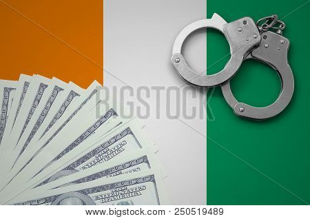 Ivory Coast Flag  With Handcuffs And A Bundle Of Dollars. The Concept Of Illegal Banking Operations 