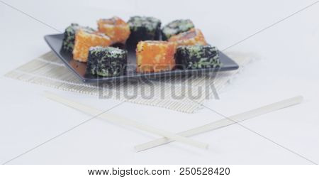Different Types Of Maki Sushi On A Black Plate.isolated On White Background