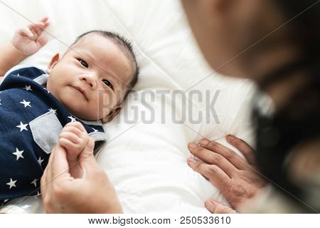 Asian Mother's Hand Holding Newborn Baby Fingers With Love And Care. Relationship Bonding Mom And Ch