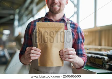 Mid Section Portrait Of Unrecognizable Smiling Man Wearing Apron Posing Holding Paper Bag Of Coffee 