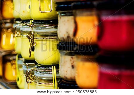 Glass Jars With Colorful Sauces Stand In A Row On The Shelves Of The Supermarket