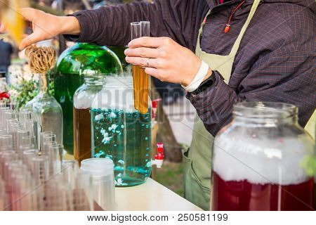 Close Up Barman Hands Holding Alcohol Tincture Cocktail In Test-tubes. Street Food Festival, Unusual