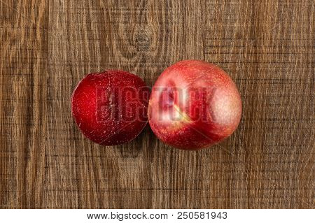 Group Of One Whole One Half Of Fresh Pluot Interspecific Plums Variety Flatlay On Brown Wood