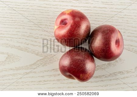Group Of Three Whole Fresh Pluot Interspecific Plums Variety Flatlay On Grey Wood