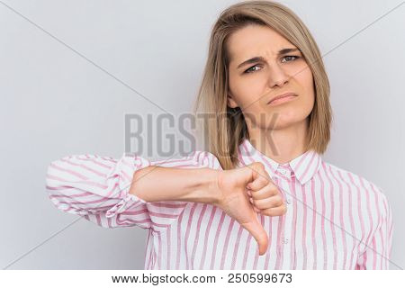 Closeup Portrait Of Unhappy Blonde Female Wears Striped Pink Shirt Looking At The Camera With Digust