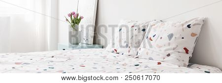 Fresh Pink Tulips In Ceramic Vase Placed On Bedside Table Standing Next To Bed With Lastrico Pattern