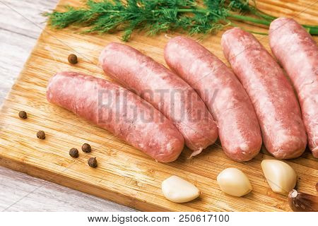 Grilled Sausages, Garlic And Dill On A Wooden Cutting Board