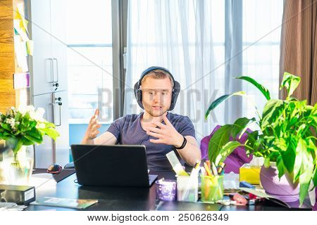 Emotional Man In Headphones Looking At Computer Screen, Gestures And Participating In Online Meeting