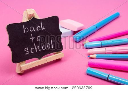 Small Blackboard With Back To School Words And School Supplies Of Bright Pink And Blue Colors On A P