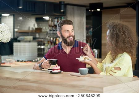 Girlfried Feeding Her Boyfriend Tasty, Delicious Cake. Boy Having Dark Hair, Beard, Wearing Burgundy
