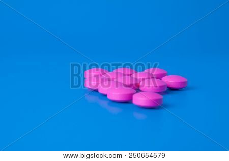 Bright Pink Pills On A Blue Background. Location In The Middle Of The Image