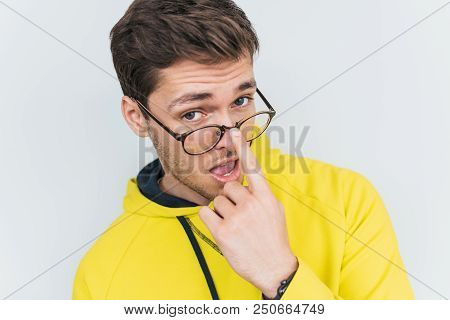 Close Up Portrait Of Interested Stunned Male Looks At Camera With Jaw Dropped Out, Touches Glasses, 