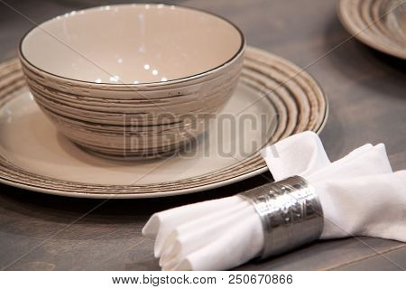 Brown Porcelain Plate, A Bowl And A White Napkin On A Wooden Table