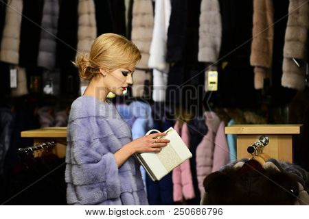 Rich Fashion Concept. Lady Looking Into White Purse Tries Expensive Grey Mink Overcoat On. Woman Wit