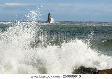 Unique High Tide Causes Large Waves To Break Around The Shore And Around A Stone Lighthouse In Maine
