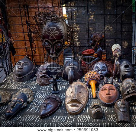 Photo Of A Merchants Table Of Various Wooden African Tribal Mask, Figurines And Wall Statues, In Har