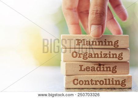 Hand Putting The Wooden Toy With Words About Four Functions Of Management: Planning, Organizing, Lea