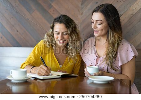 Female Coworkers In Casual Clothes Discussing Ideas. Smiling Female University Students Working On P